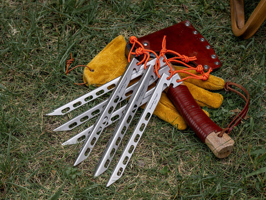 Boundless Voyage titanium tent stakes with orange reflective cord, yellow work gloves and camping hammer on green grass