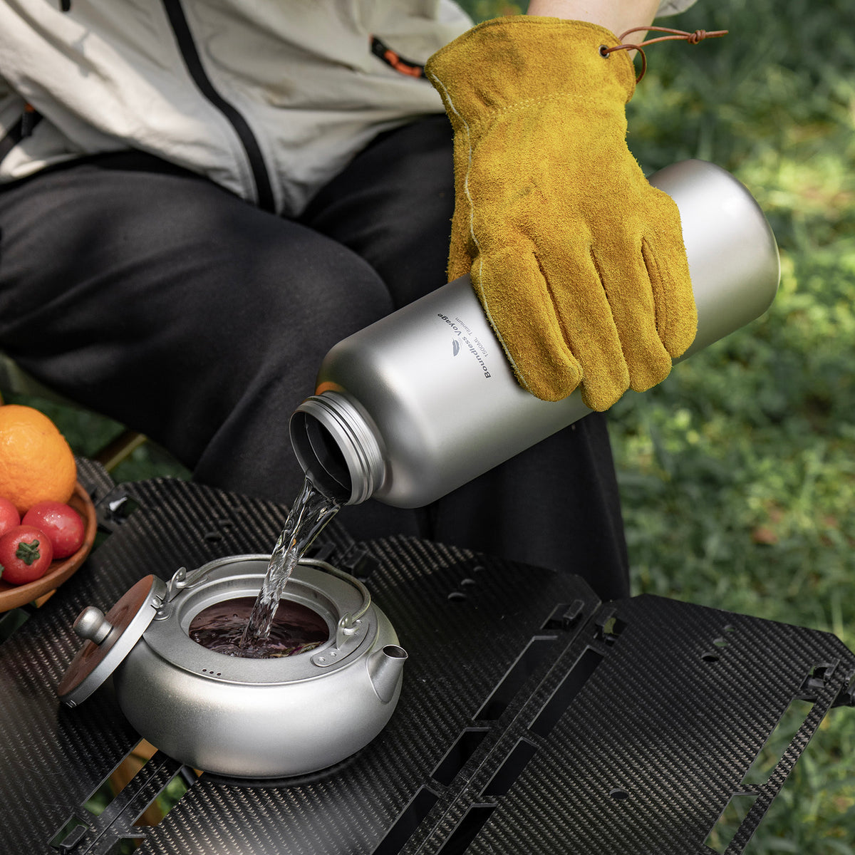 Pouring fresh water from 1500ml titanium bottle into outdoor titanium teapot
