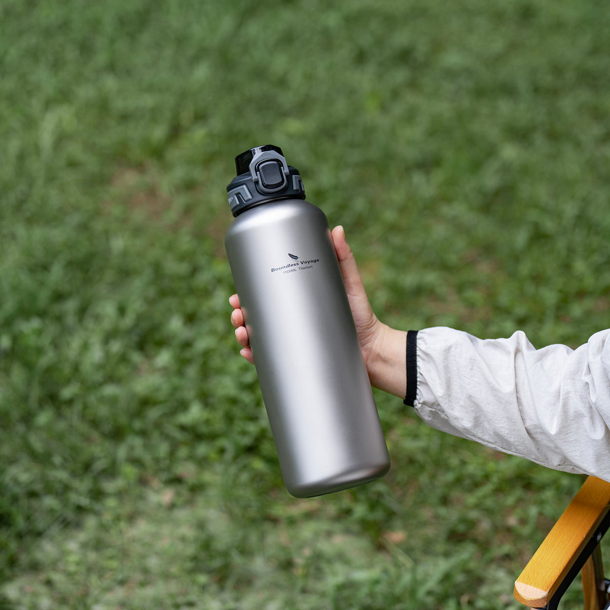Hand holding Boundless Voyage 1500ml titanium water bottle with PP flip lid outdoors