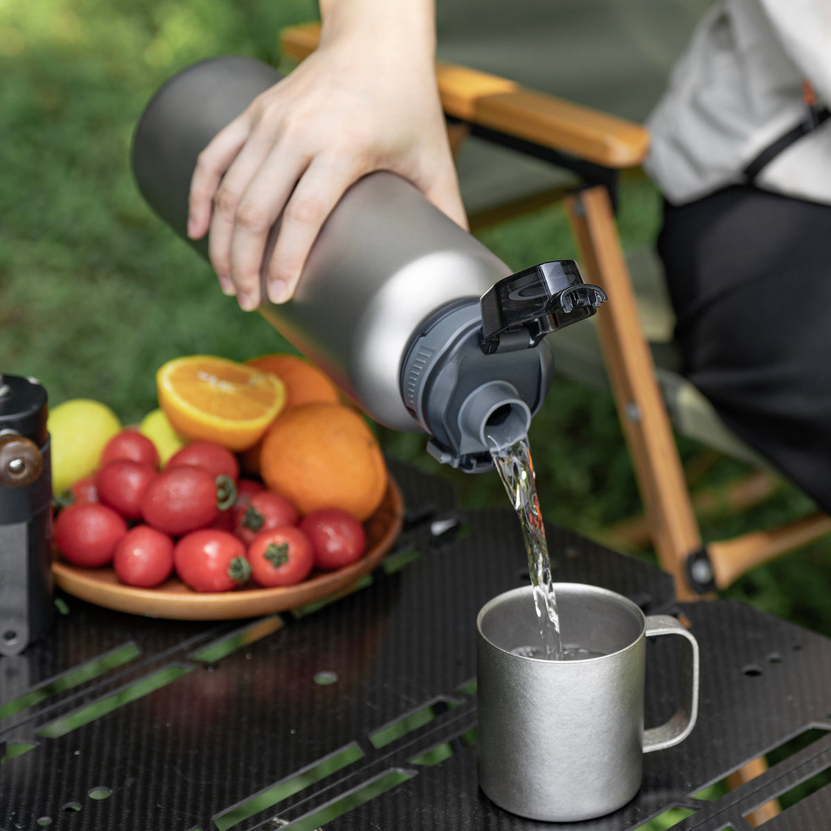 Pouring water through PP flip-top spout into titanium coffee mug at camp table