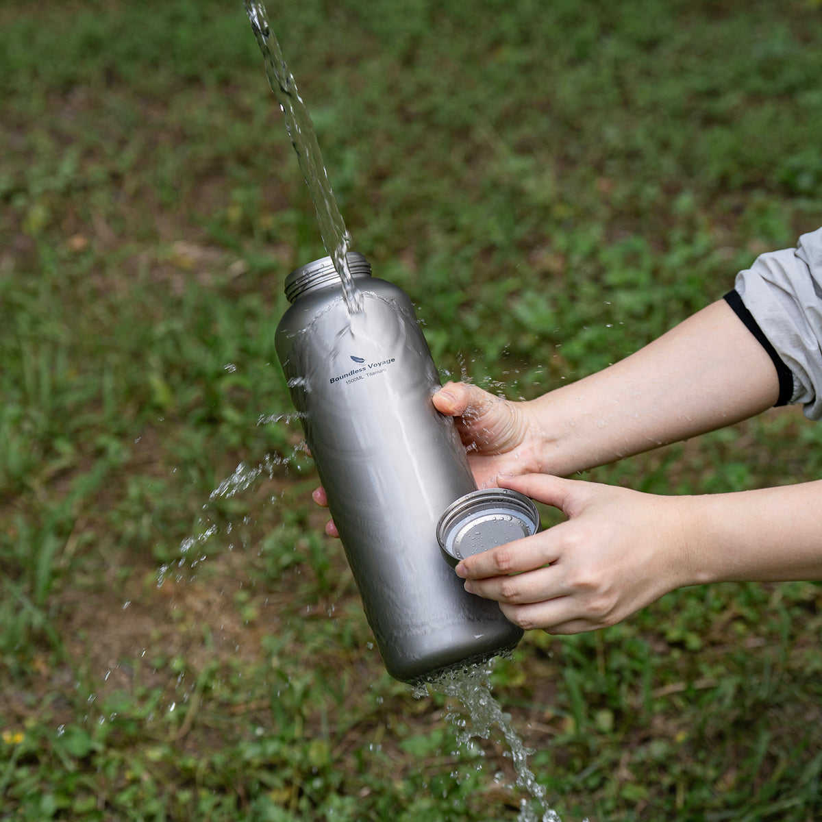Rinsing the exterior of pure titanium water bottle with clean water outdoors