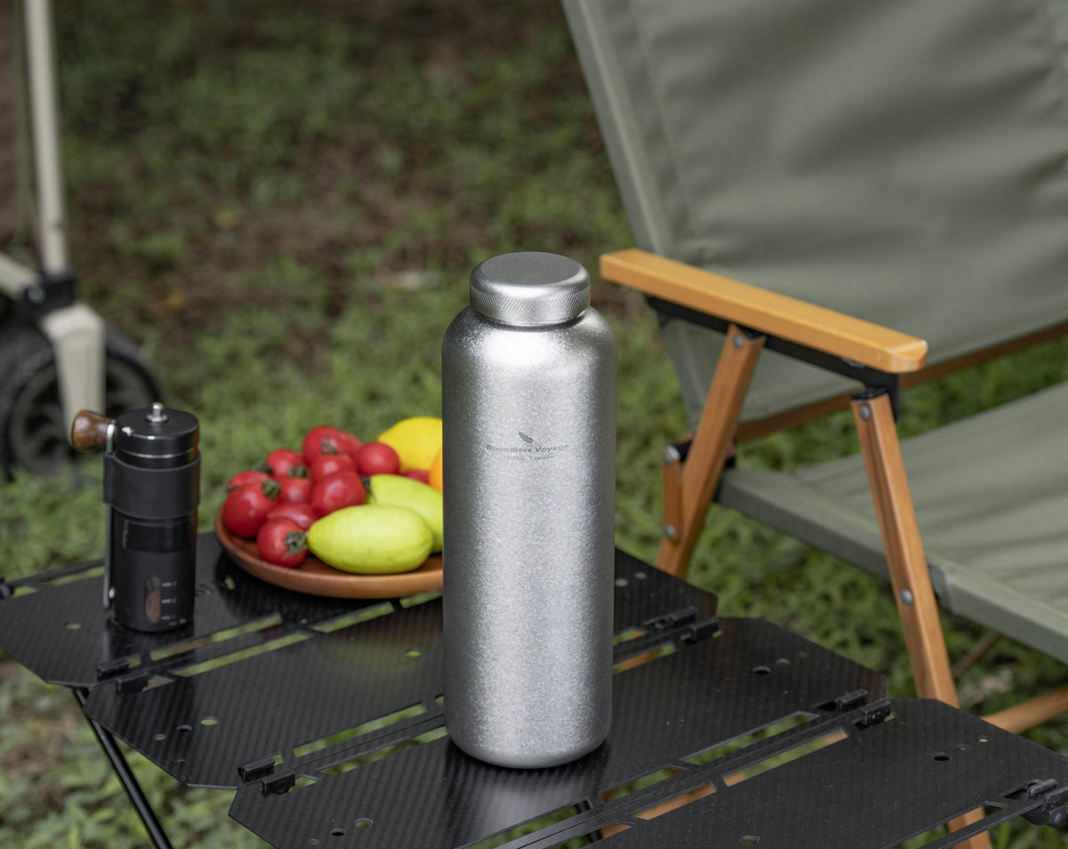 Crystallized silver titanium water bottle with titanium screw cap on outdoor camping table