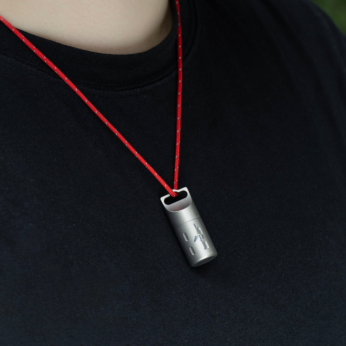 Ti9009A titanium pill case worn around neck with included red lanyard for hands-free carry