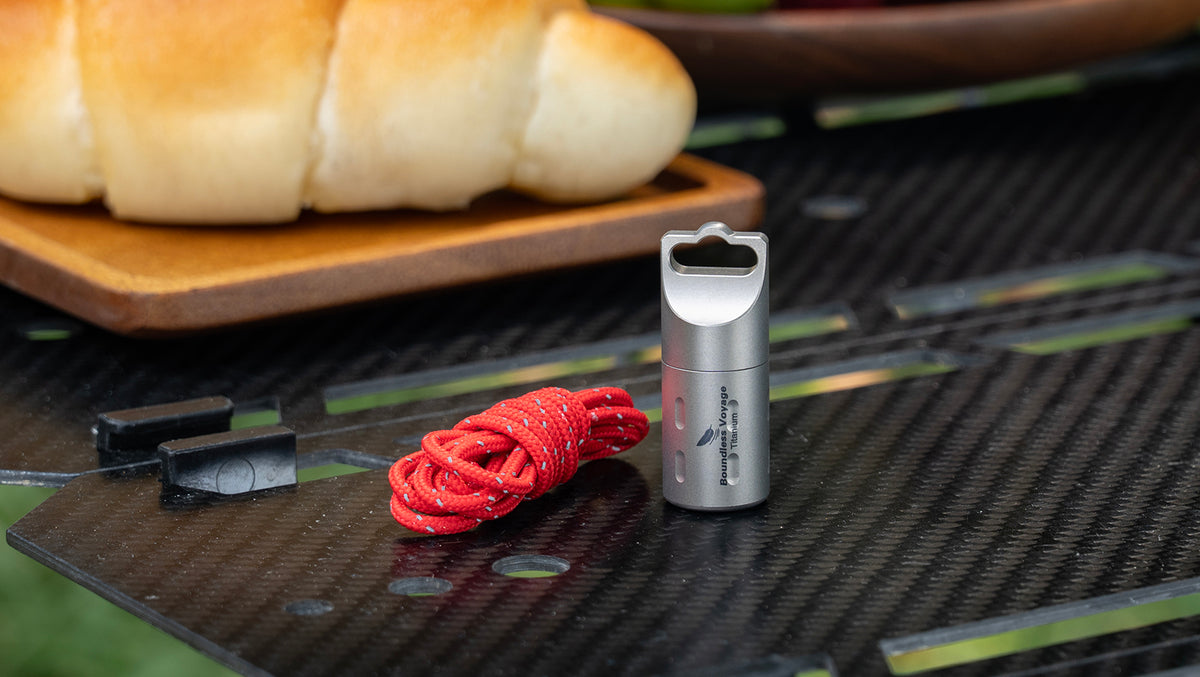 Boundless Voyage Ti9009A titanium pill box and red lanyard on camping table