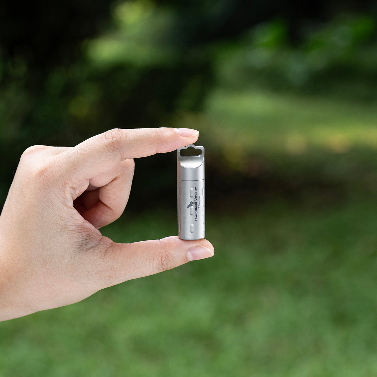 Ti9009B long titanium pill case hanging vertically with red cord outdoors