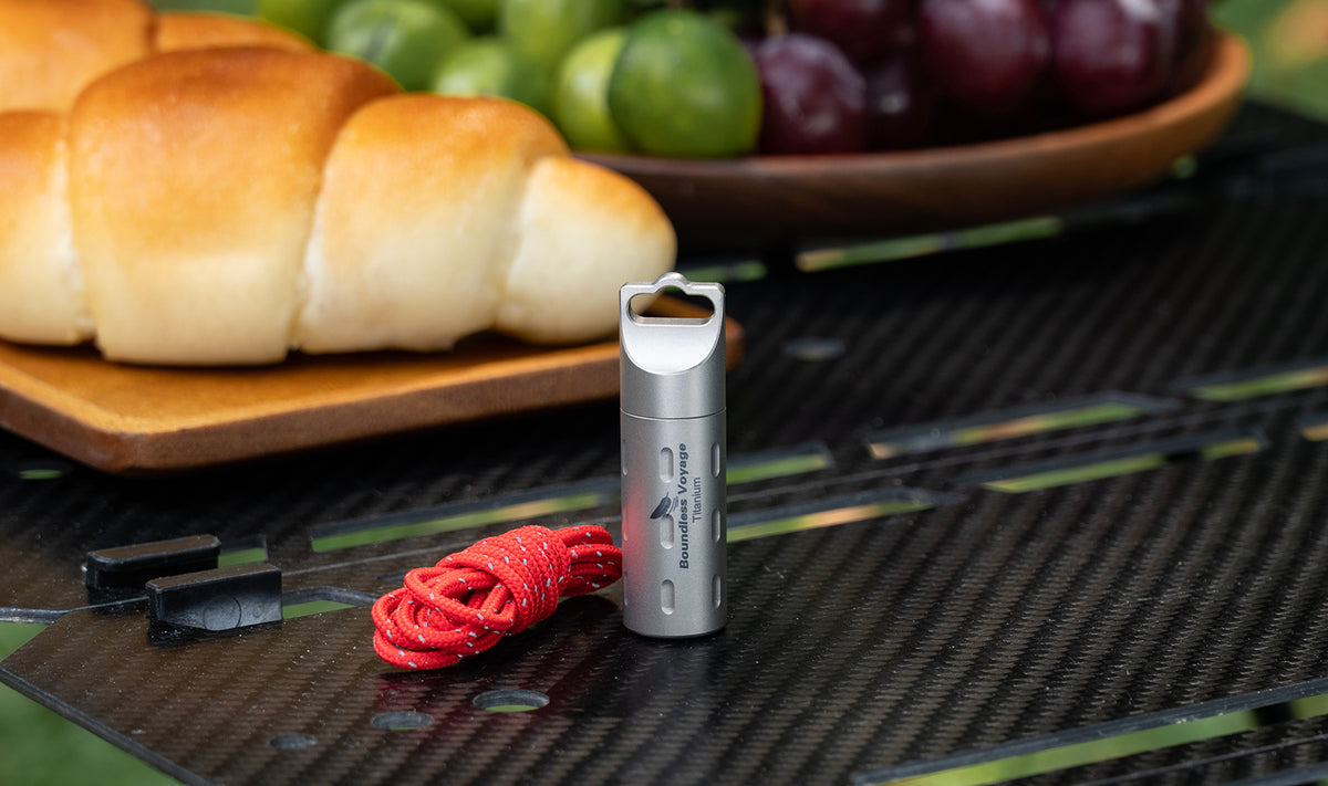 Ti9009B elongated pure titanium pill stash and red lanyard on outdoor table