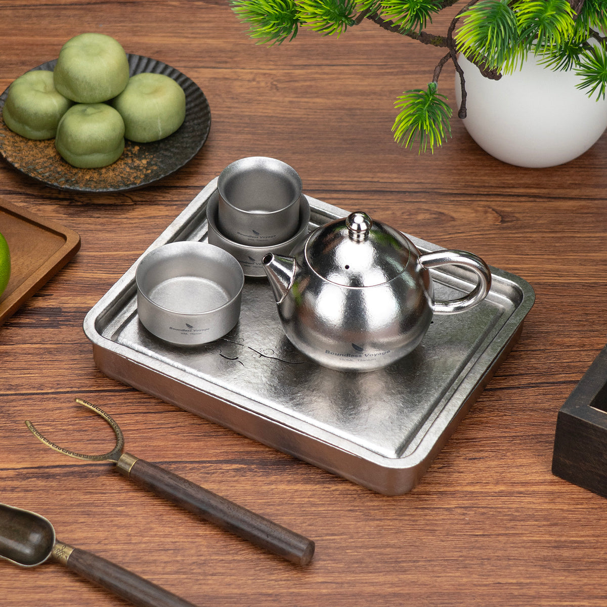 Titanium teapot and stacked double-wall tea cups resting on the square tea tray 