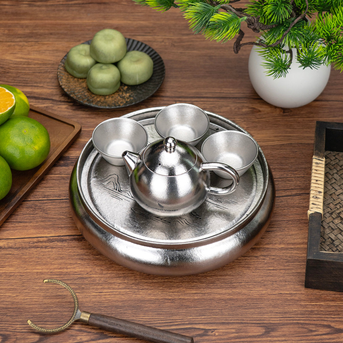 Boundless Voyage round titanium tea tray arranged with teapot and three double-wall cups on wooden table