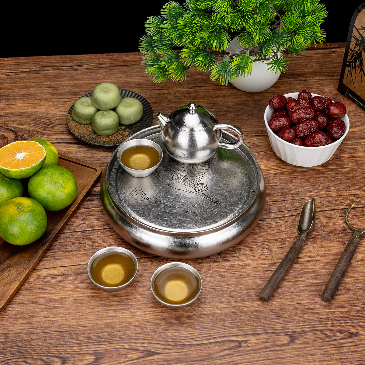 Titanium teapot and stacked tea cups placed on the ice-crystalline round tea tray