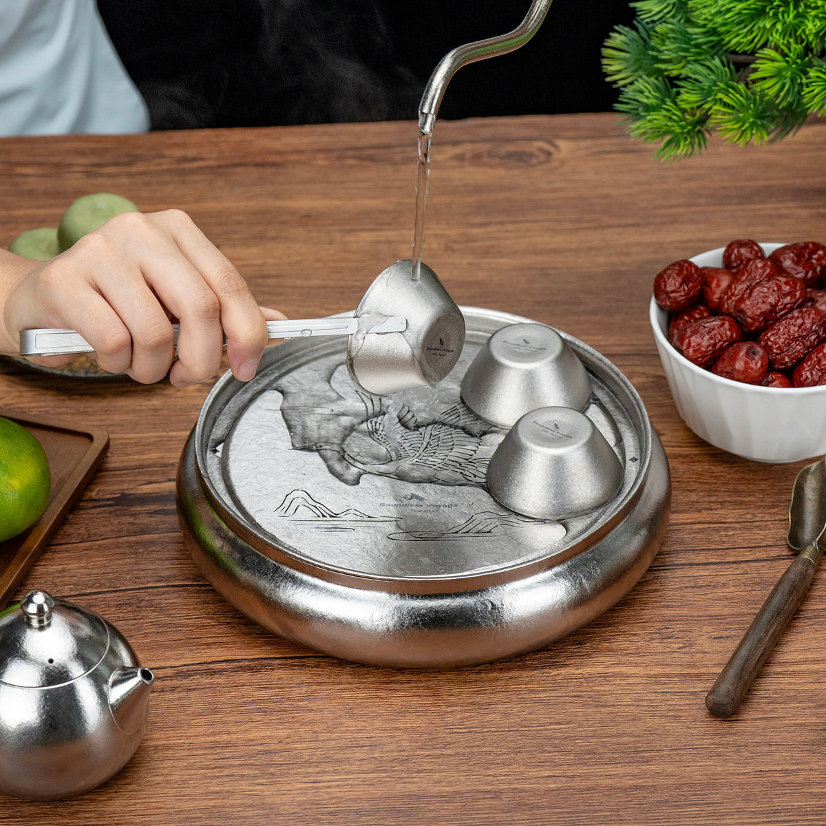 Rinsing titanium tea cups with hot water over the round tea tray drainage plate