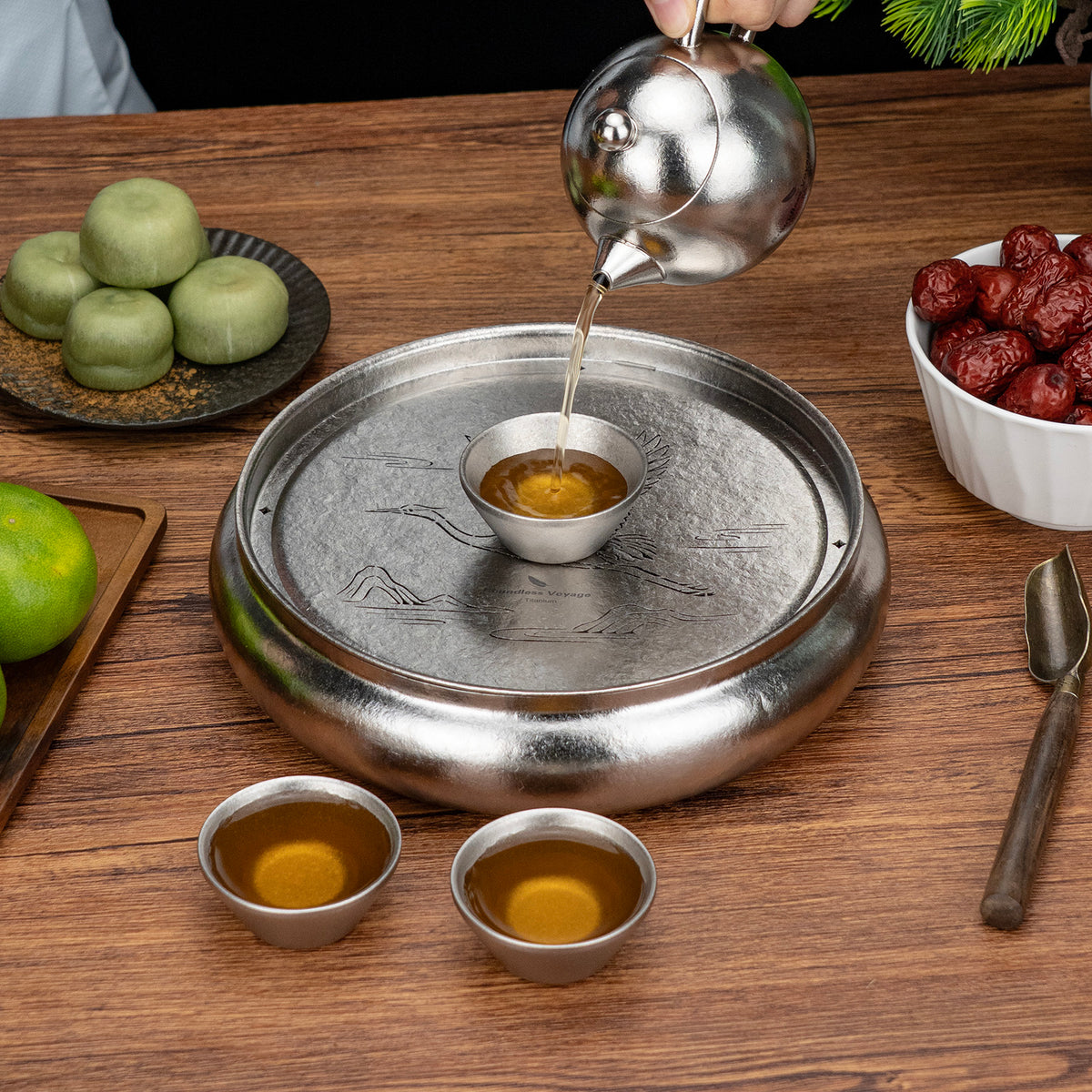 Pouring freshly brewed tea from titanium teapot into cup on the round tea tray