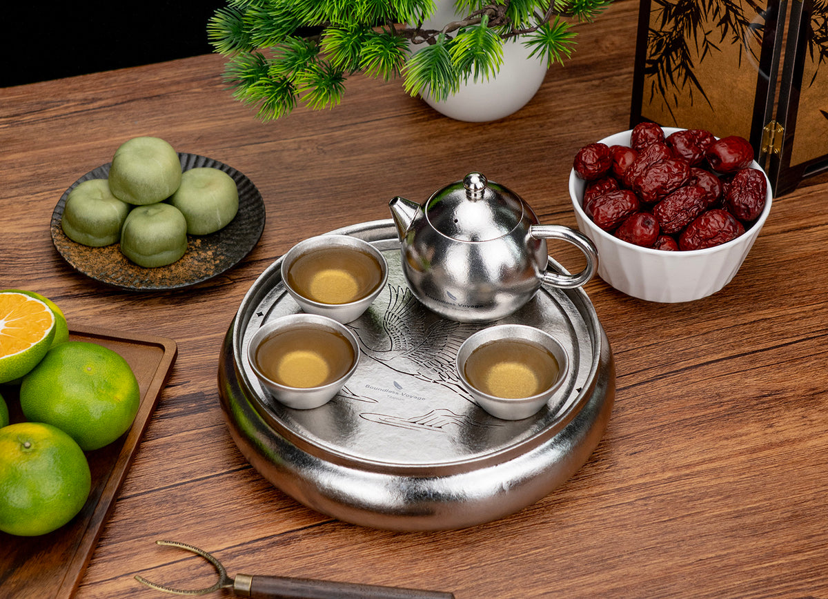 Full titanium Gongfu tea ceremony setup with round tea tray, teapot, three cups, and tea snacks